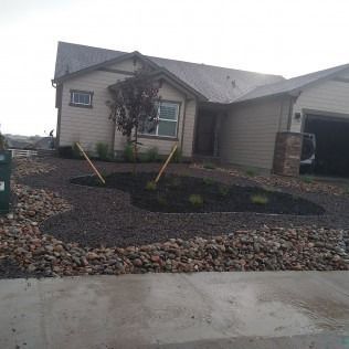 Single-story house with rock landscaping, small tree, and front walkway under cloudy sky