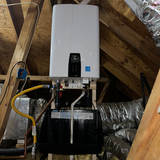Tankless water heater mounted in an attic, with gas and water lines connected.