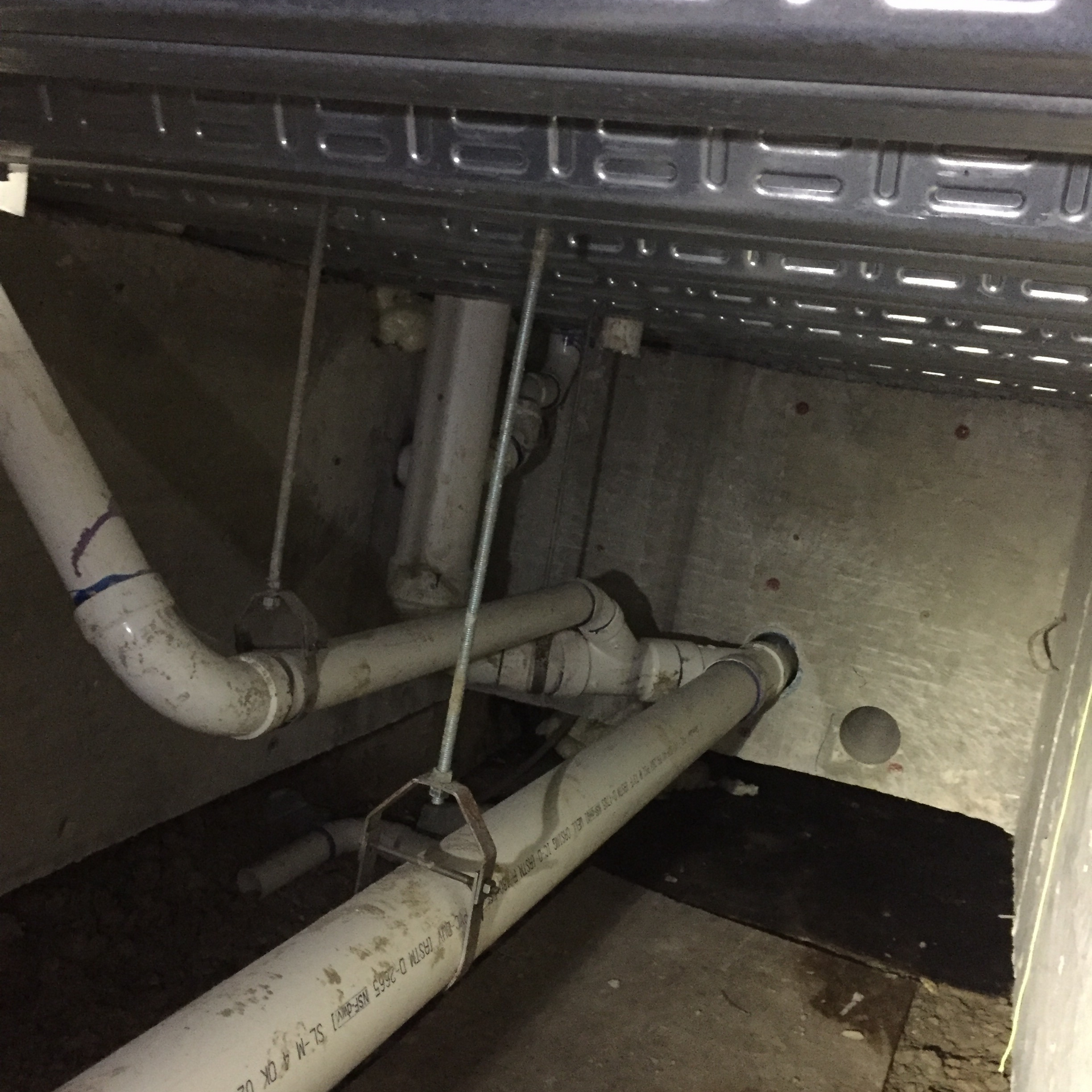 Pipes and metal components in an enclosed space, potentially an appliance or utility area.