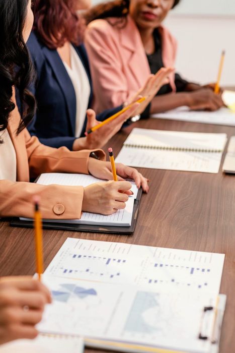 Personas sentadas en una mesa de conferencias tomando notas durante una reunión.