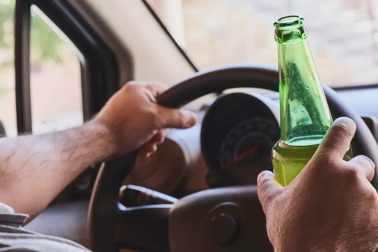 A man drinking beer while driving, illustrating DUI charges in Ontario