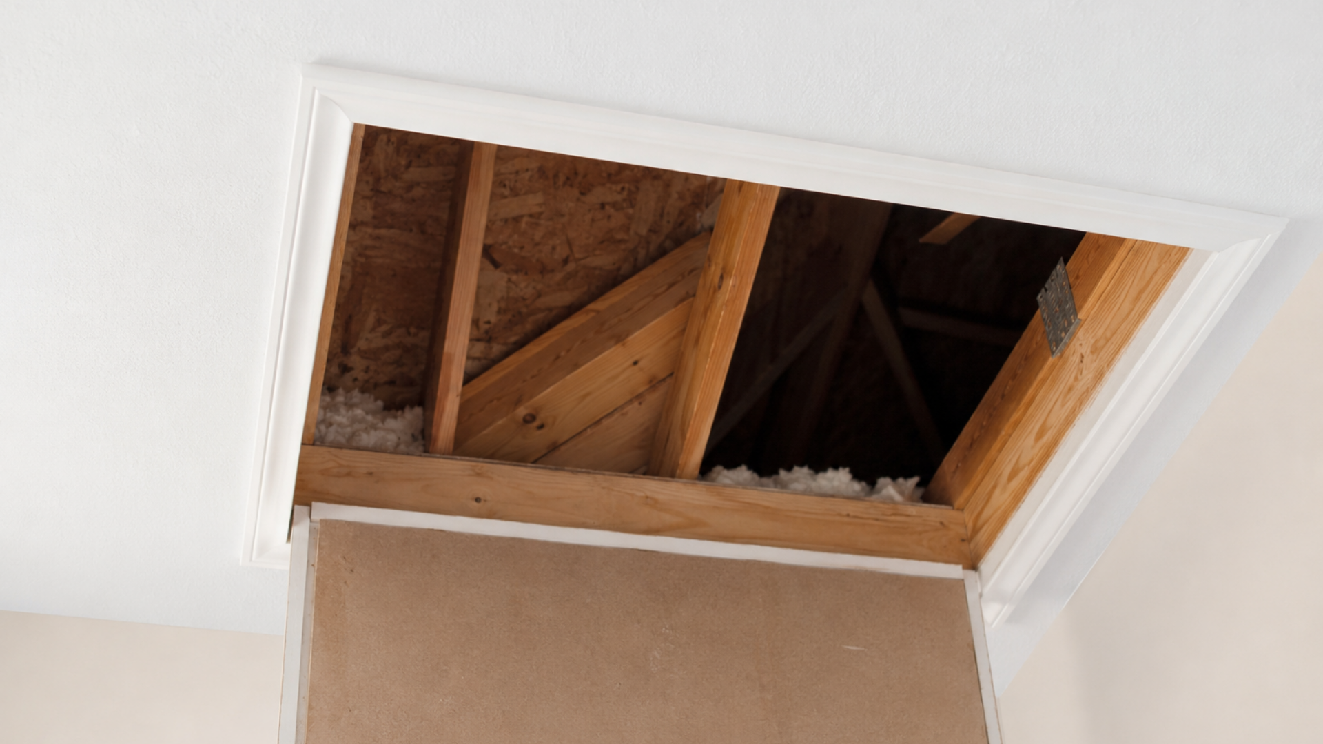 Open ceiling hatch revealing exposed wooden attic framing and insulation