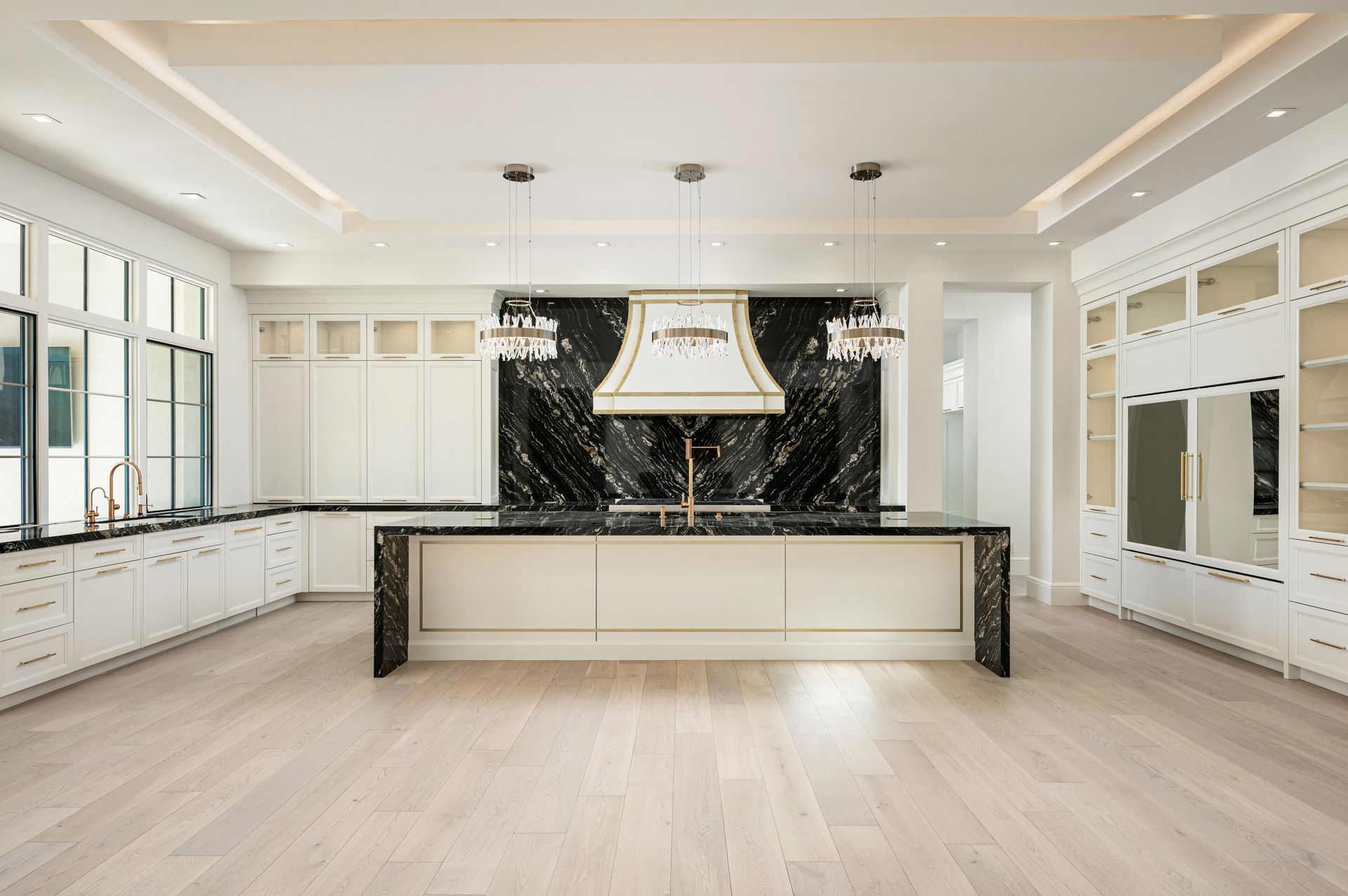 Bright, modern kitchen with white cabinets, pale wood floors, and a large black-and-white island centerpiece