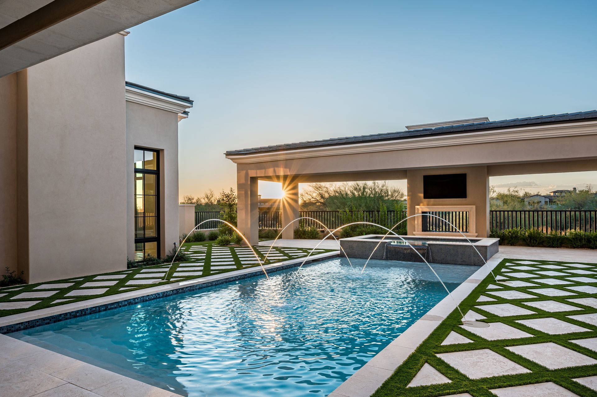 Modern villa courtyard with a blue pool, geometric lawn, and sunset light
