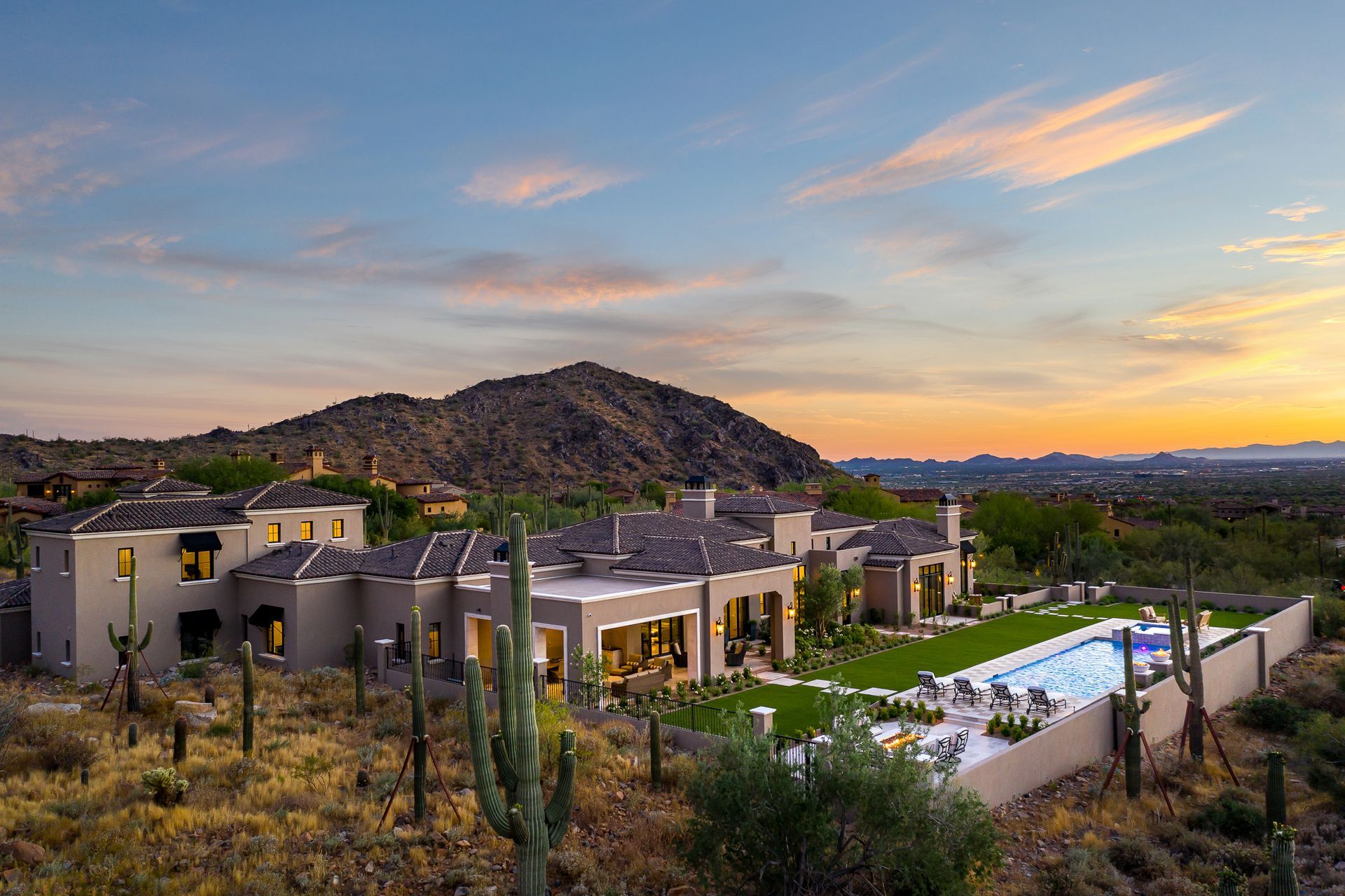 Modern hillside custom home build at sunset with a mountain backdrop and pool