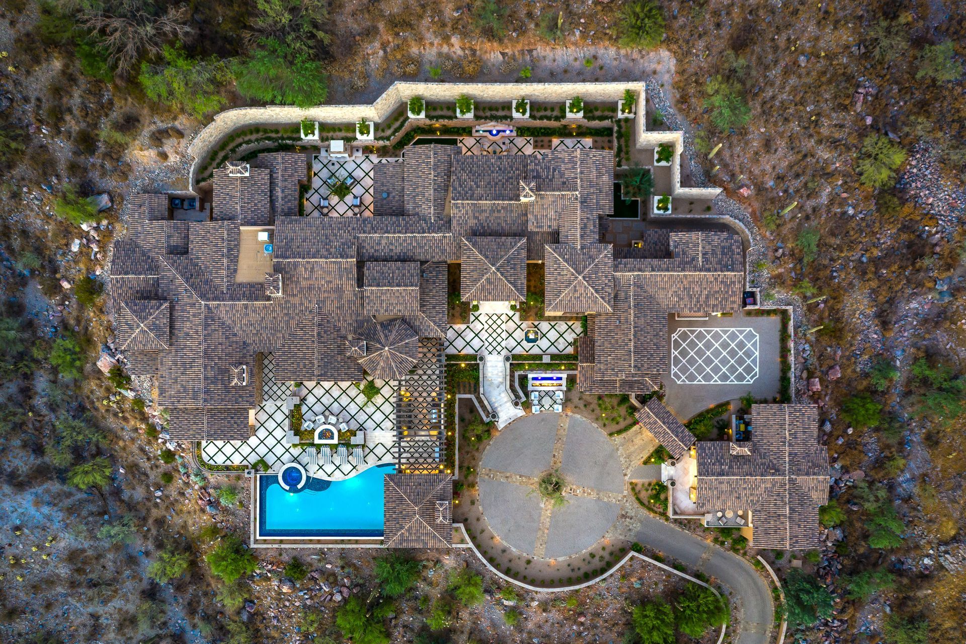 Aerial view of French villa luxury home on a hill with a sweeping driveway and pool in front