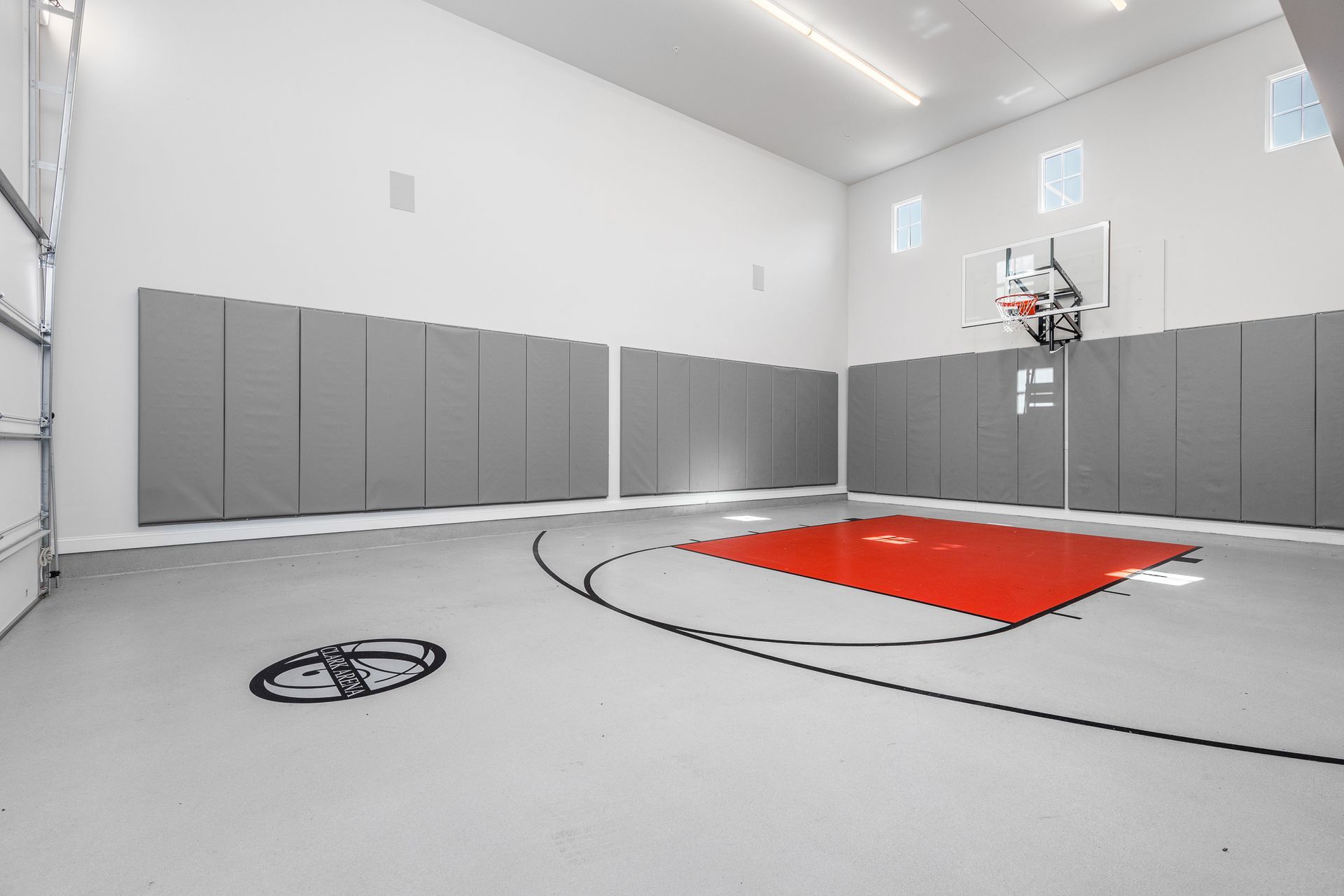 Indoor basketball court with gray walls, a red key, and a hoop on the far wall.
