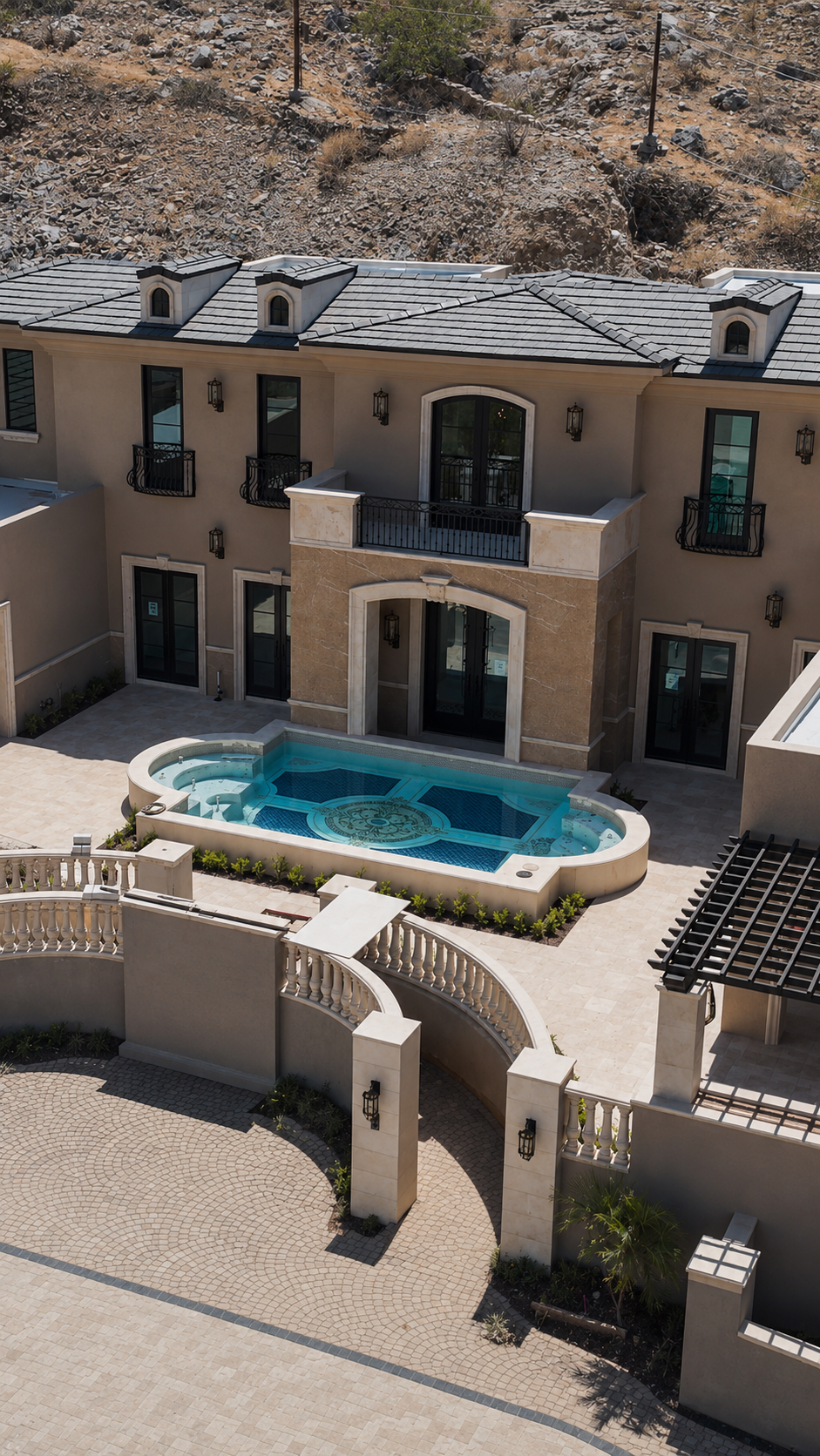 Luxury hillside mansion with a turquoise pool, balcony, and gated courtyard in a desert setting