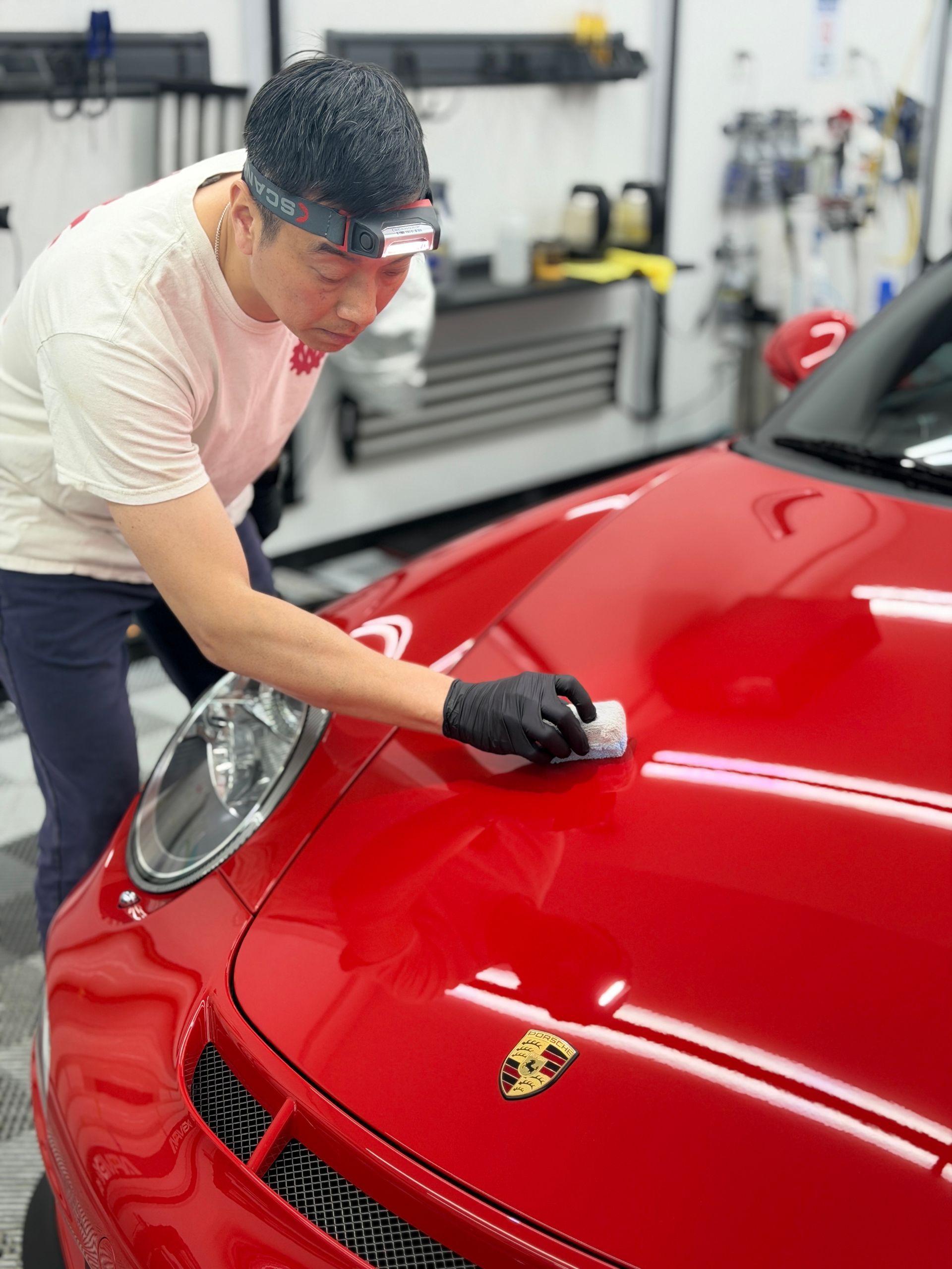 Person polishing a red Porsche in a garage workshop