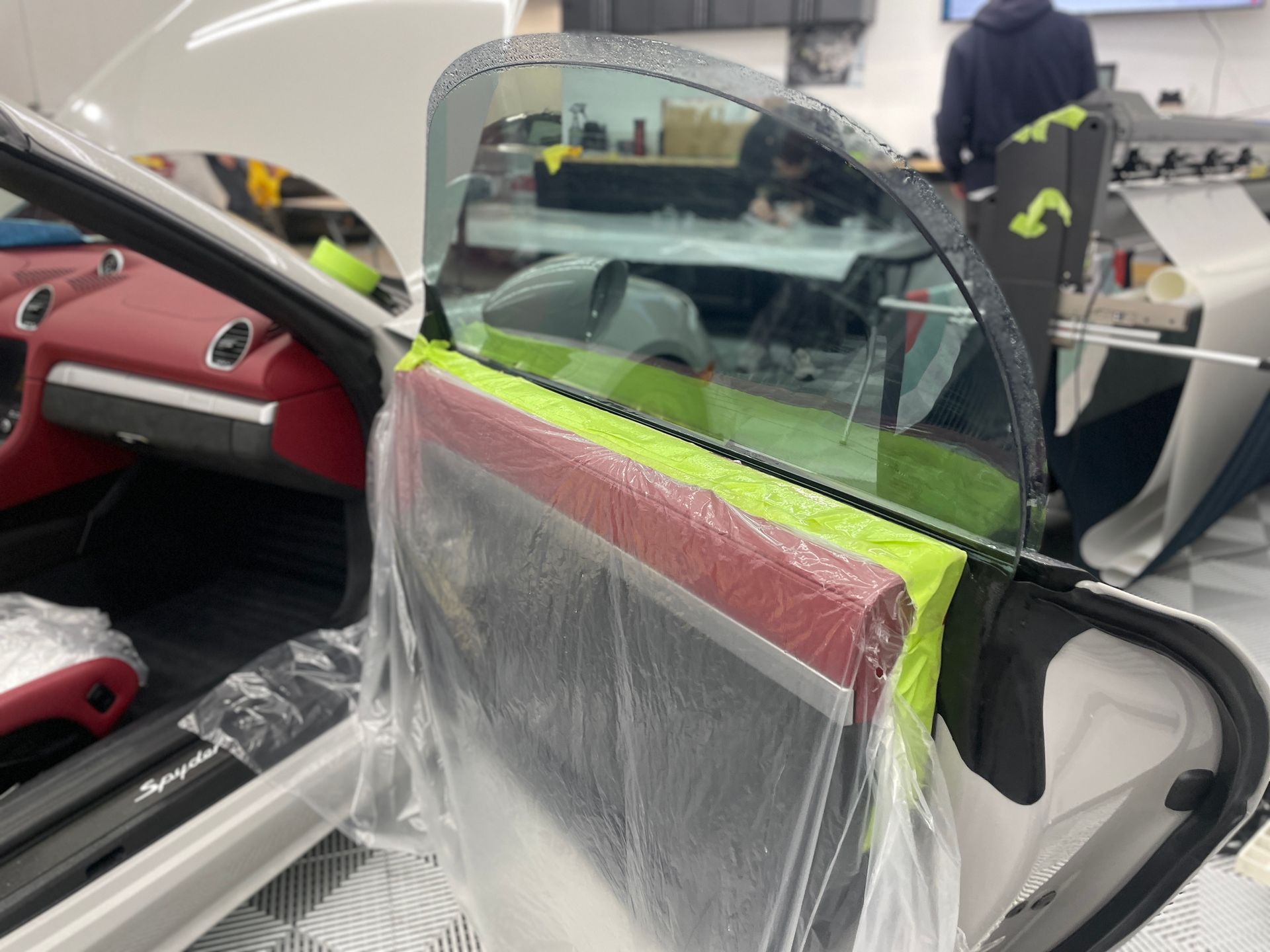 Car interior with a shattered window being repaired, red and black seats visible