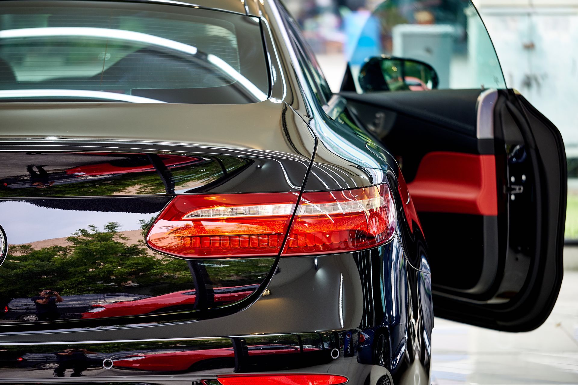 Black luxury car with the rear door open, shown in a showroom or garage.
