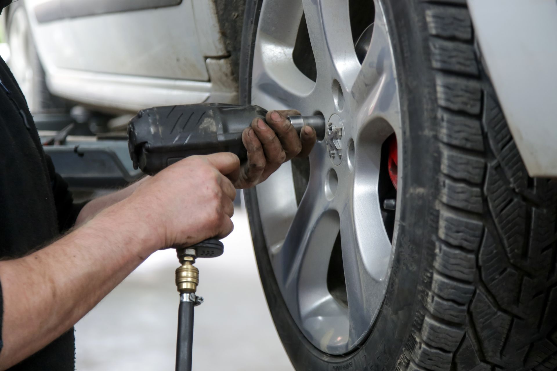 Mechanic using an air impact wrench to tighten a car wheel lug nut