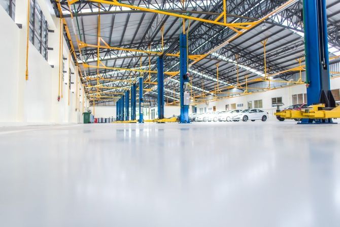 Bright empty warehouse interior with blue columns, yellow beams, and polished white floor