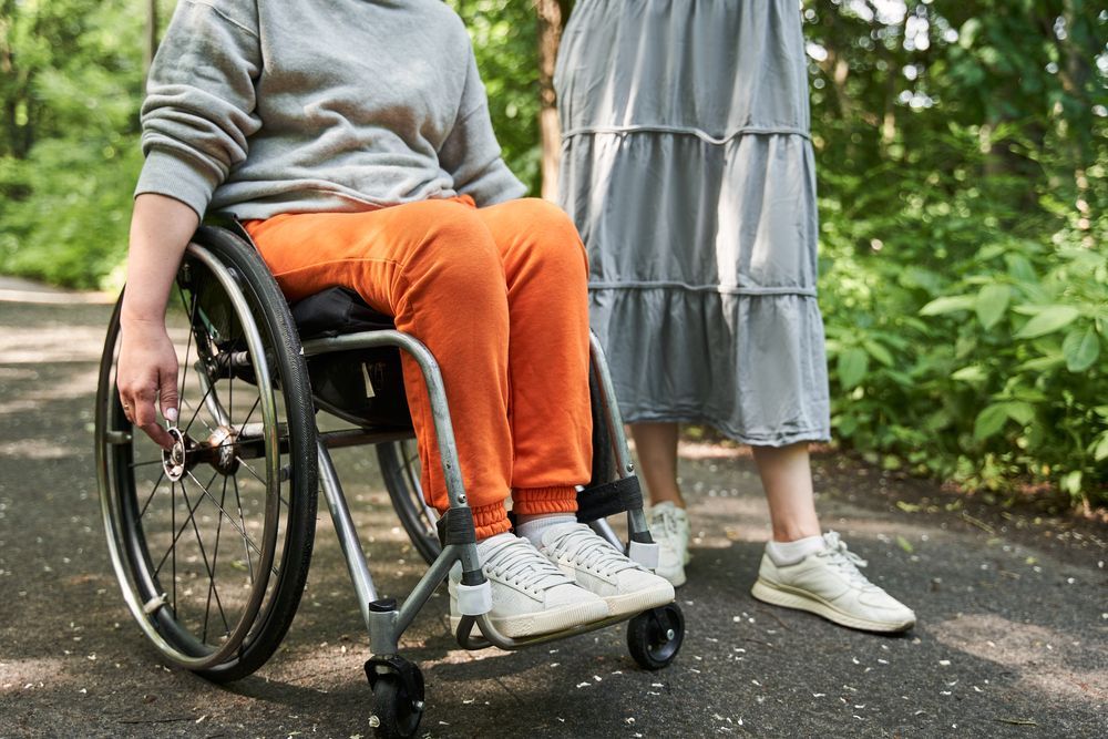 Person in Wheelchair on Path With Person Standing Nearby — Dwyer Law Group in Surfers Paradise, QLD