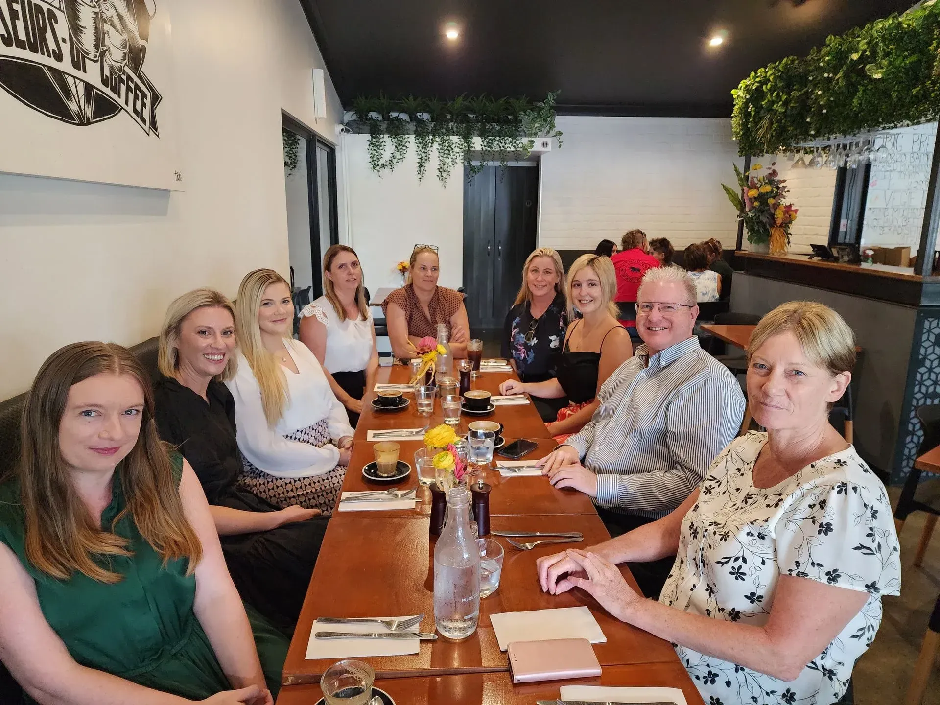 A Group of People Sitting Around a Table in a Cafe — Dwyer Law Group in Surfers Paradise, QLD 