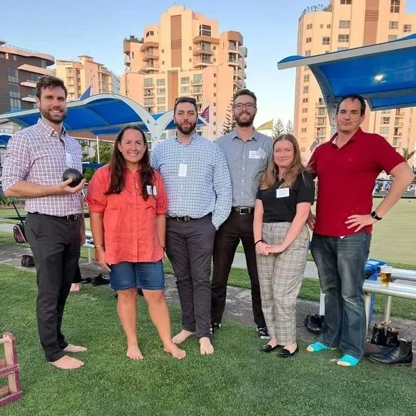 Group of Six People Posing on a Lawn, Buildings in the Background — Dwyer Law Group in Surfers Paradise, QLD