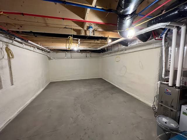 Attic with exposed wooden rafters, silver HVAC ducts, and pink insulation between ceiling joists