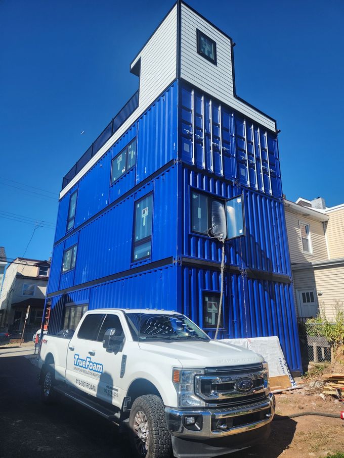 Blue two-story building under construction with a white pickup truck parked in front.