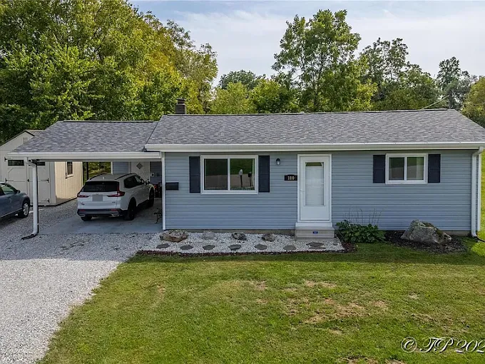 Single-story gray house with attached carport, white car, and green front lawn.