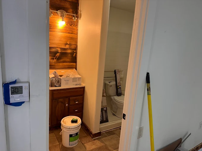 Bathroom renovation with vanity, sink, and toilet in a doorway, plus tools and supplies in the hall