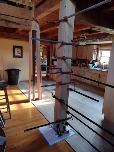 Indoor timber staircase under construction in a loft, with exposed beams and tools on the floor.