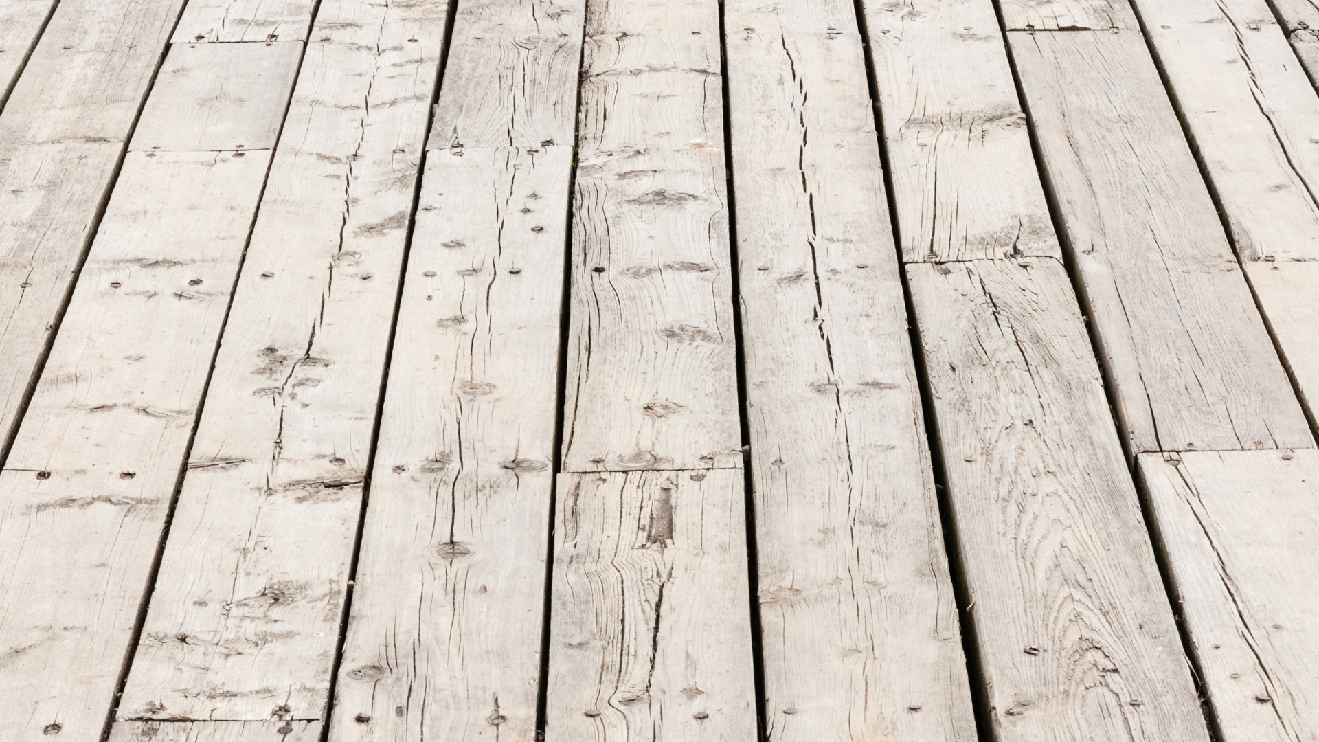 White weathered wooden plank floor with visible grain and gaps between boards