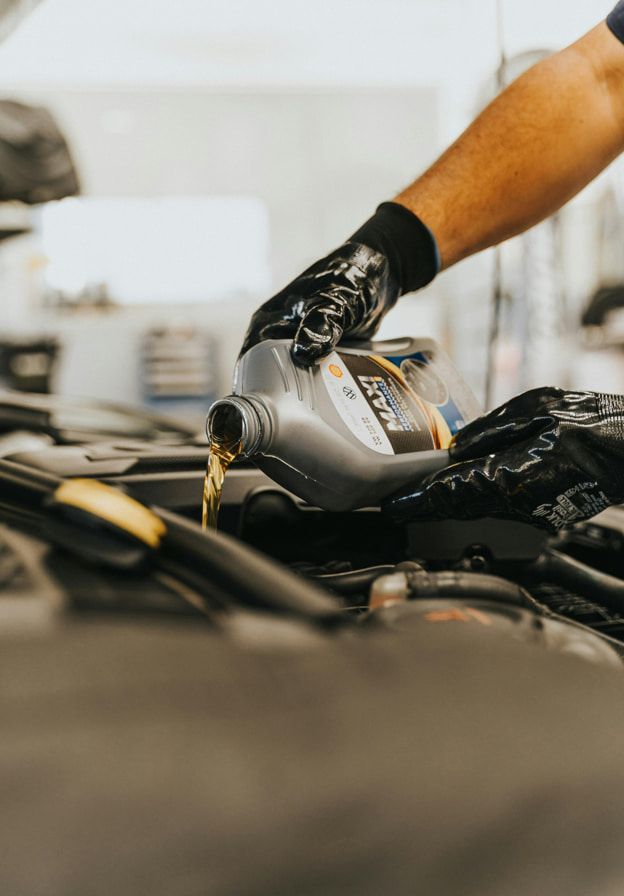 A Person is Pouring Oil Into a Car Engine — Red Central Towing & Recovery In Alice Springs, NT