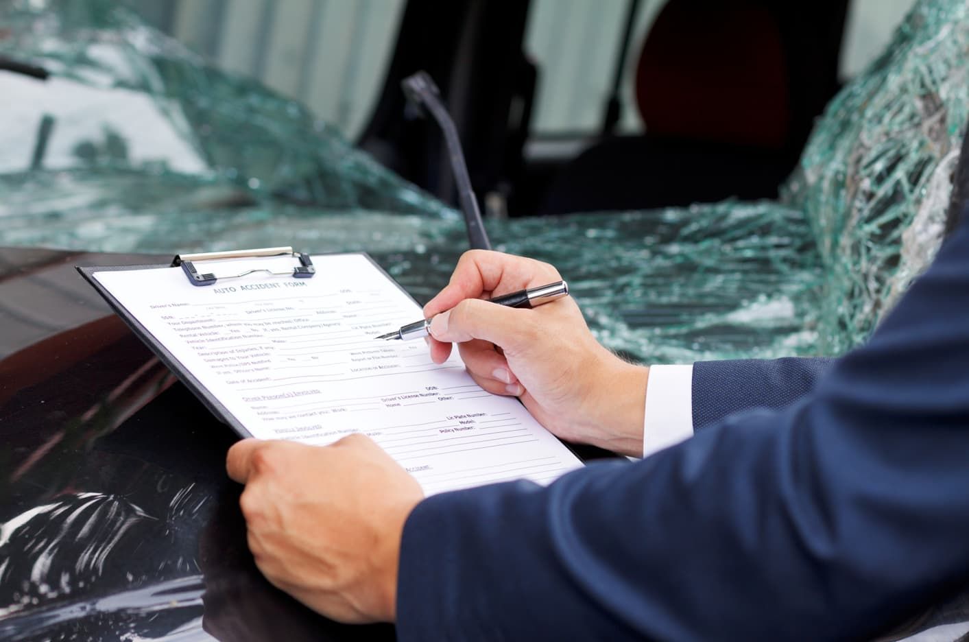 A Man is Writing on a Clipboard in Front of a Damaged Car — Red Central Towing & Recovery In Alice Springs, NT
