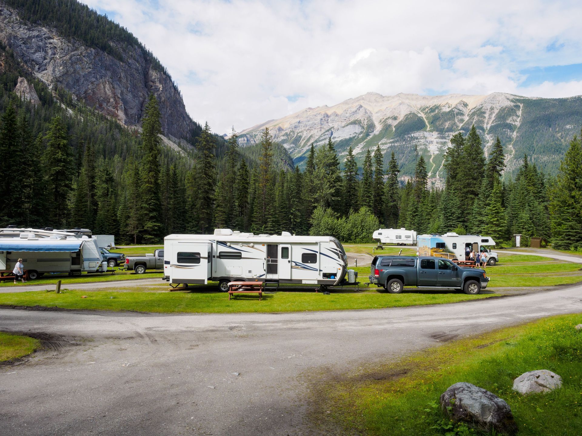 Travel trailers and motorhomes parked at an RV campground — every rig's roof takes the same sun and rain as your house