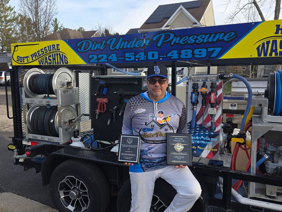 Man leaning against a trailer with water tanks, wearing a blue and white logo shirt and hat.