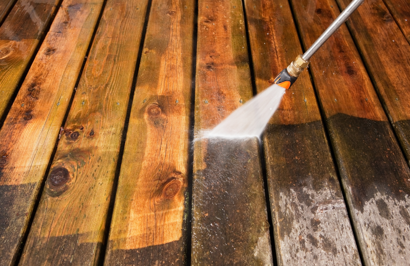 Pressure washer cleaning wooden deck, removing dirt and grime.