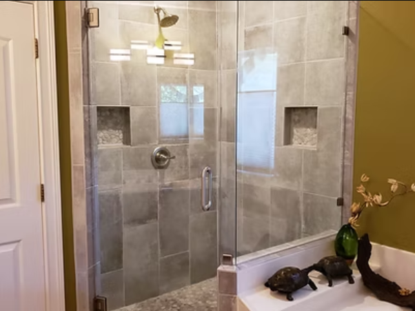 Modern bathroom with a glass shower, gray tile, and decorative niches.