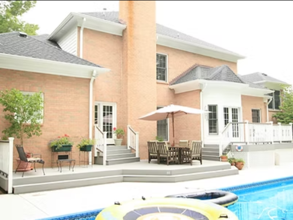 Brick house with deck, pool, and outdoor seating.
