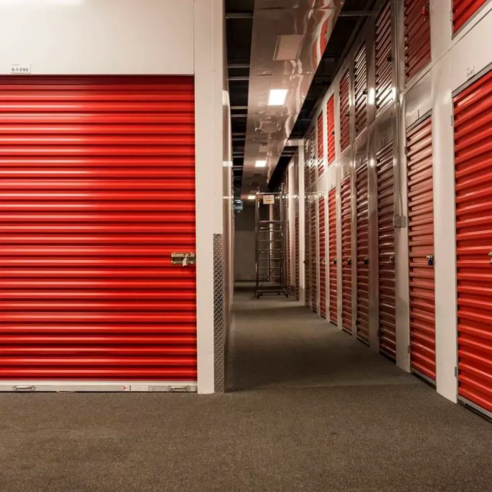 Corredor de guarda móveis com portas vermelhas.