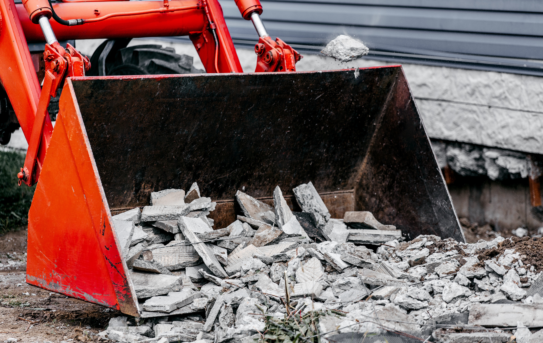 A bulldozer is scooping up concrete and rocks from the ground.