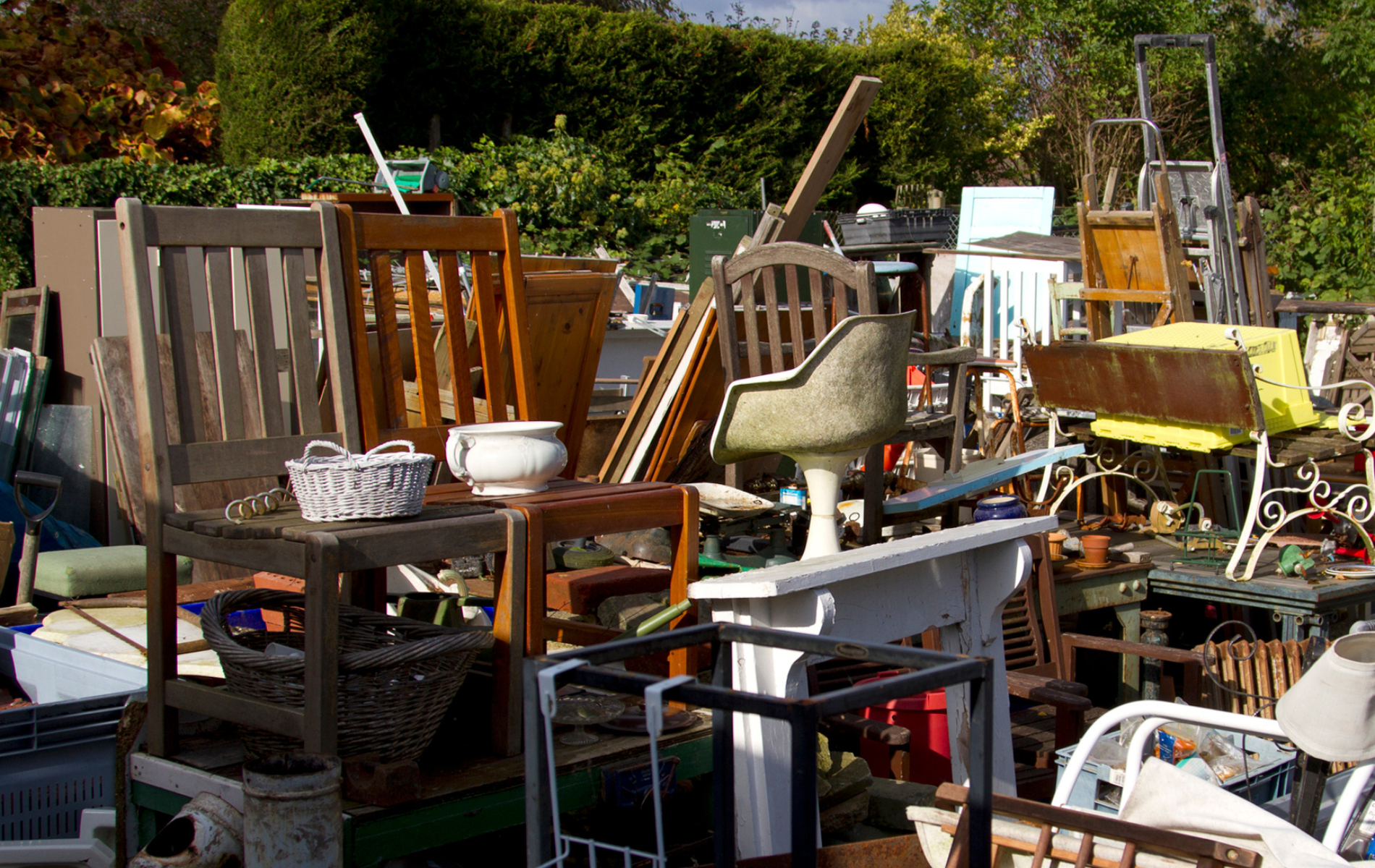 A pile of furniture is sitting on top of each other in a yard.