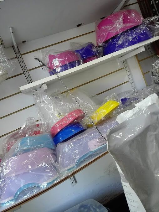 En una tienda, se ven estantes llenos de pilas de coloridos cuencos de plástico para mascotas, envueltos individualmente en envases de plástico transparente.