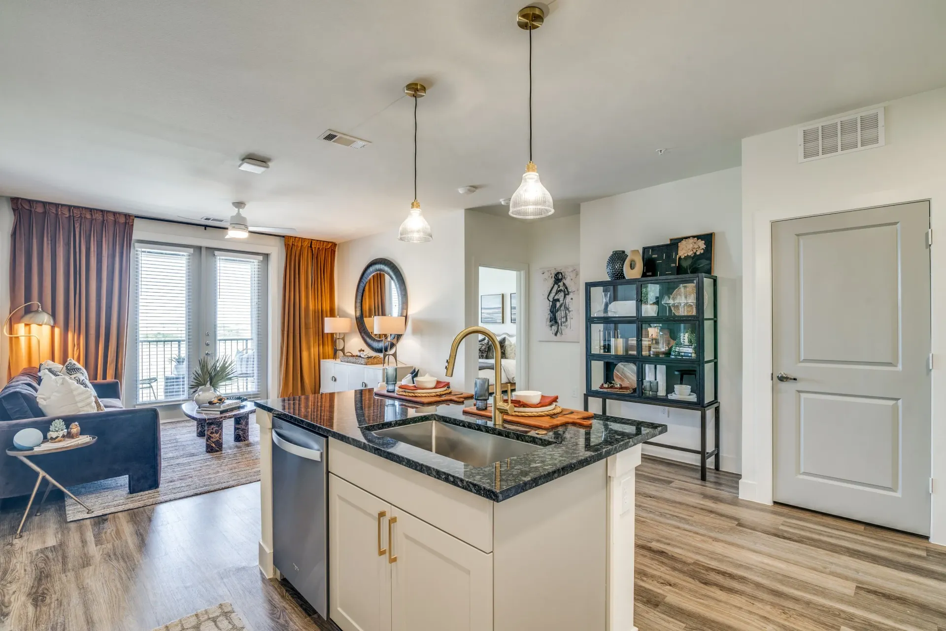 Modern kitchen island with sink and faucet, overlooking a living room area.
