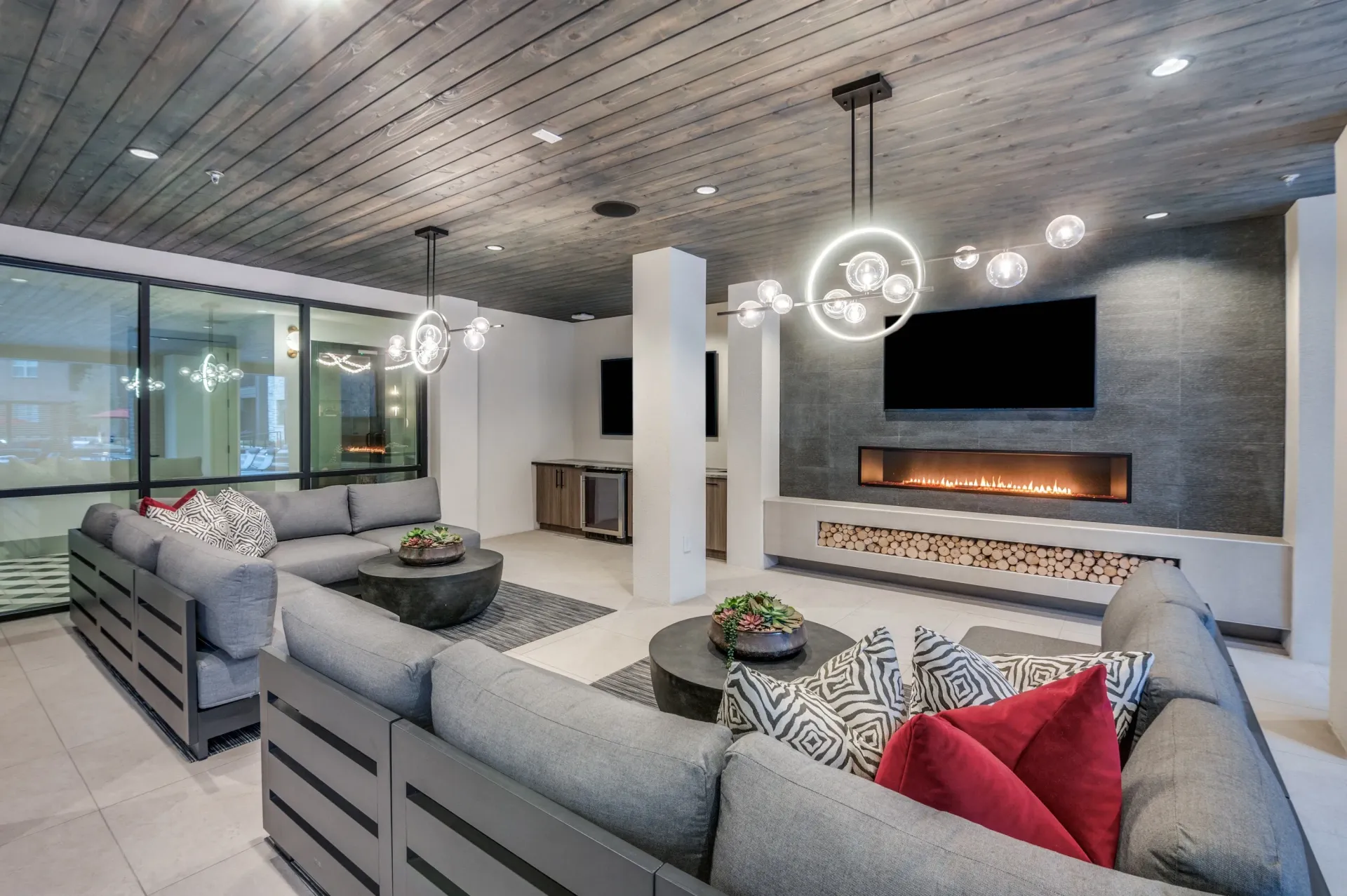 Modern lounge area with sectional sofas, modern circular light fixtures, and a linear fireplace.