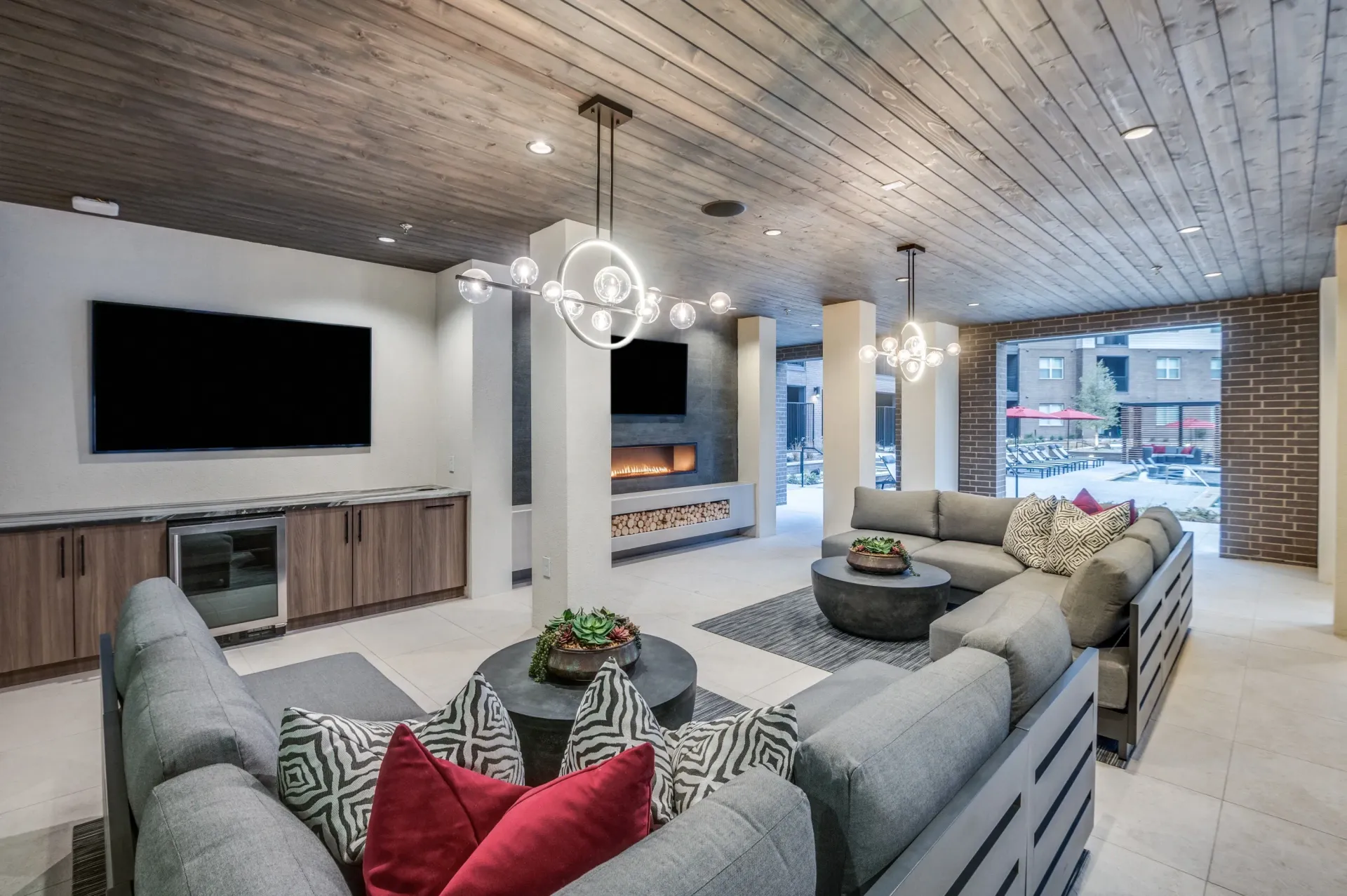 Modern lounge area with fireplace, entertainment system, and view of the pool.