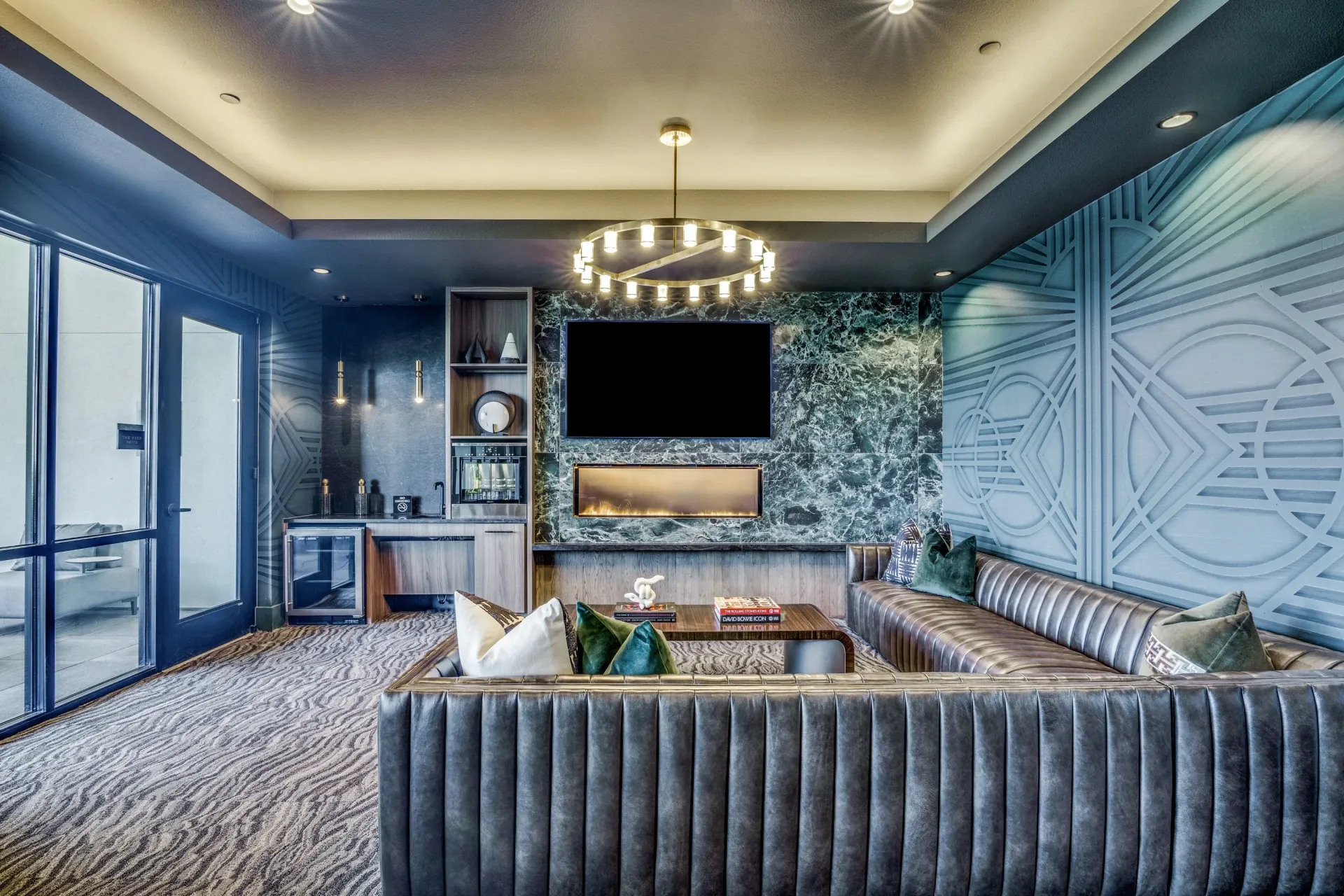 Modern lounge area with plush seating, a bar, a TV, and a fireplace.