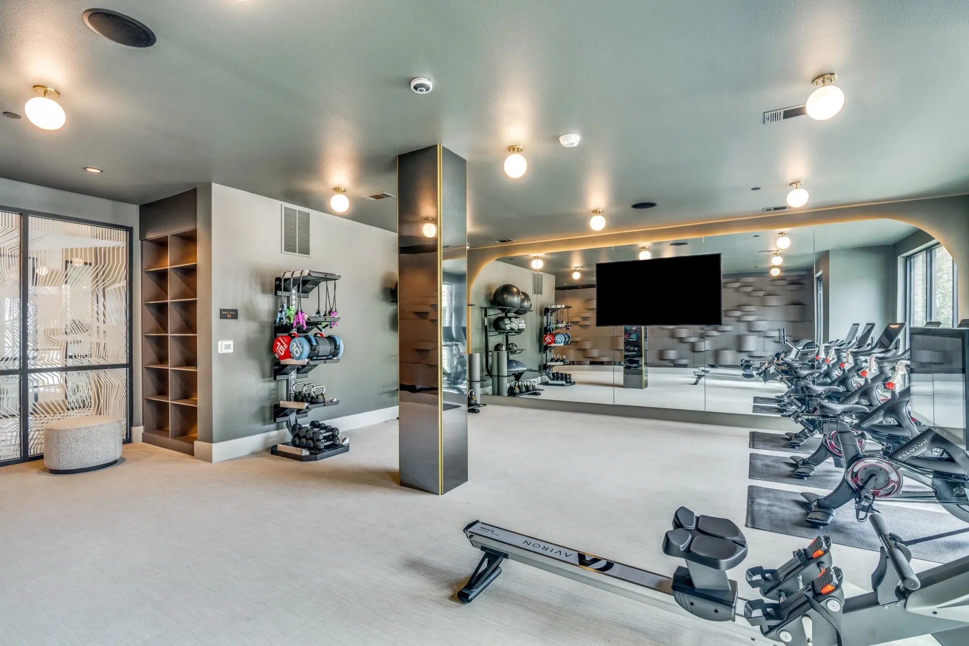 Fitness center with rowing machine, spin bikes, weights, and mirrored wall.