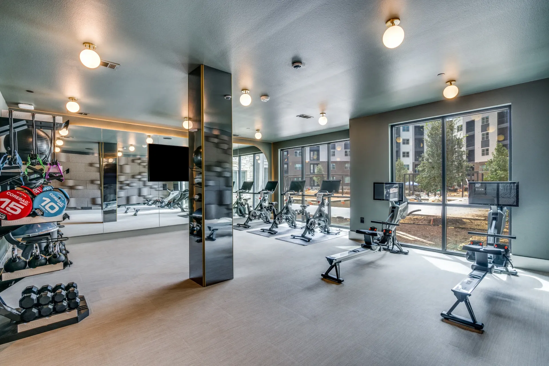 Modern apartment gym with spin bikes, rowing machines, and free weights.