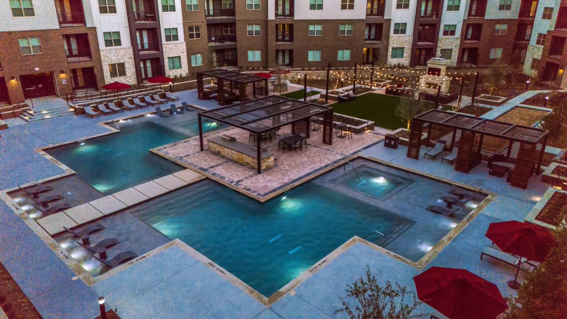 Luxury apartment community pool and spa area with lounge chairs, cabanas, and outdoor kitchen.