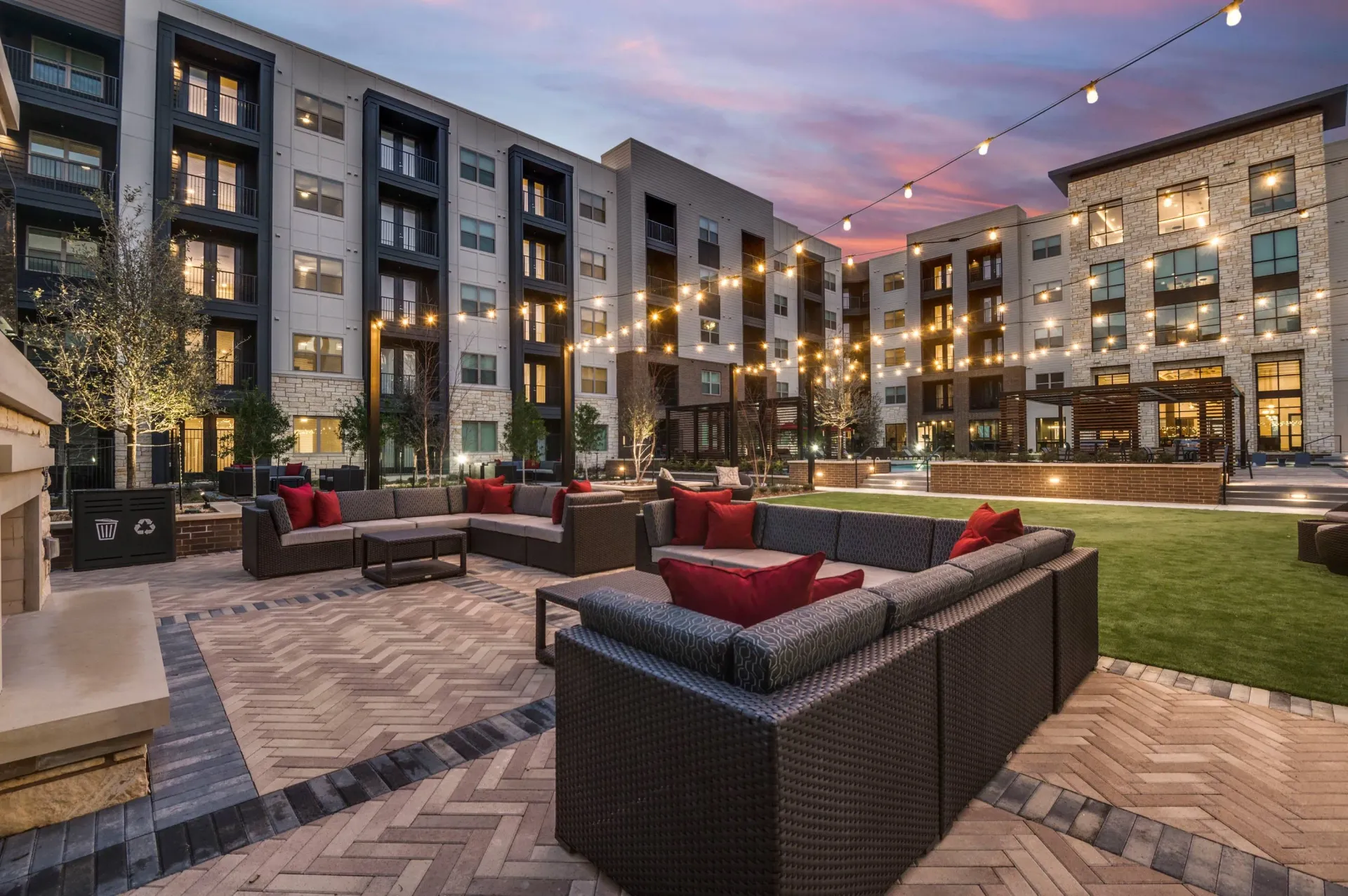 Courtyard lounge area with sectional sofas and string lights.