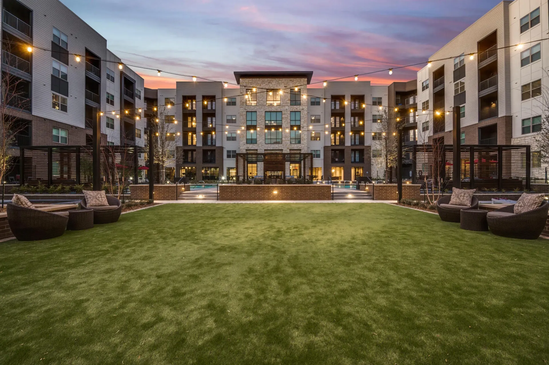 Courtyard with lounge seating and string lights at dusk