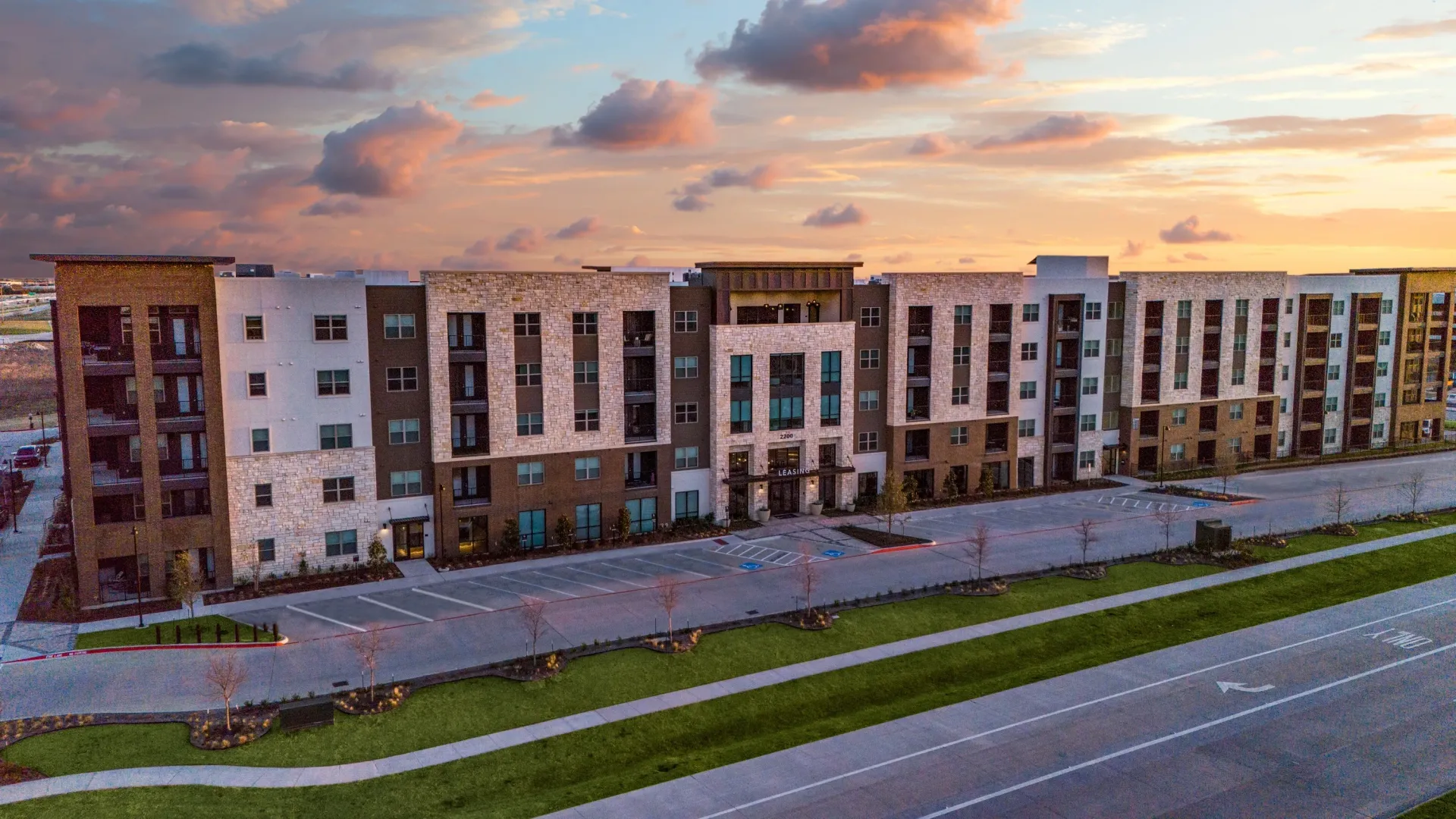 Exterior view of a modern apartment building with a beautiful sunset sky.