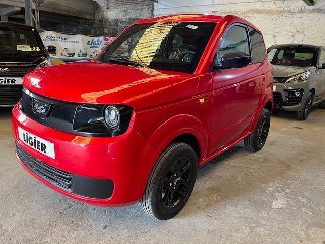 Une ligier rouge est garée dans un garage à côté d'autres voitures.