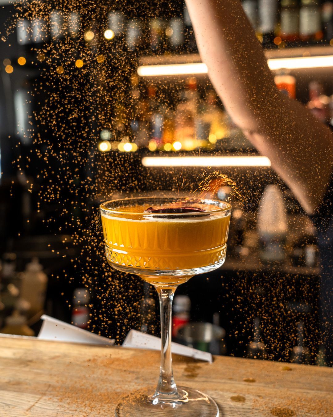 Cocktail being dusted with spices at a bar.