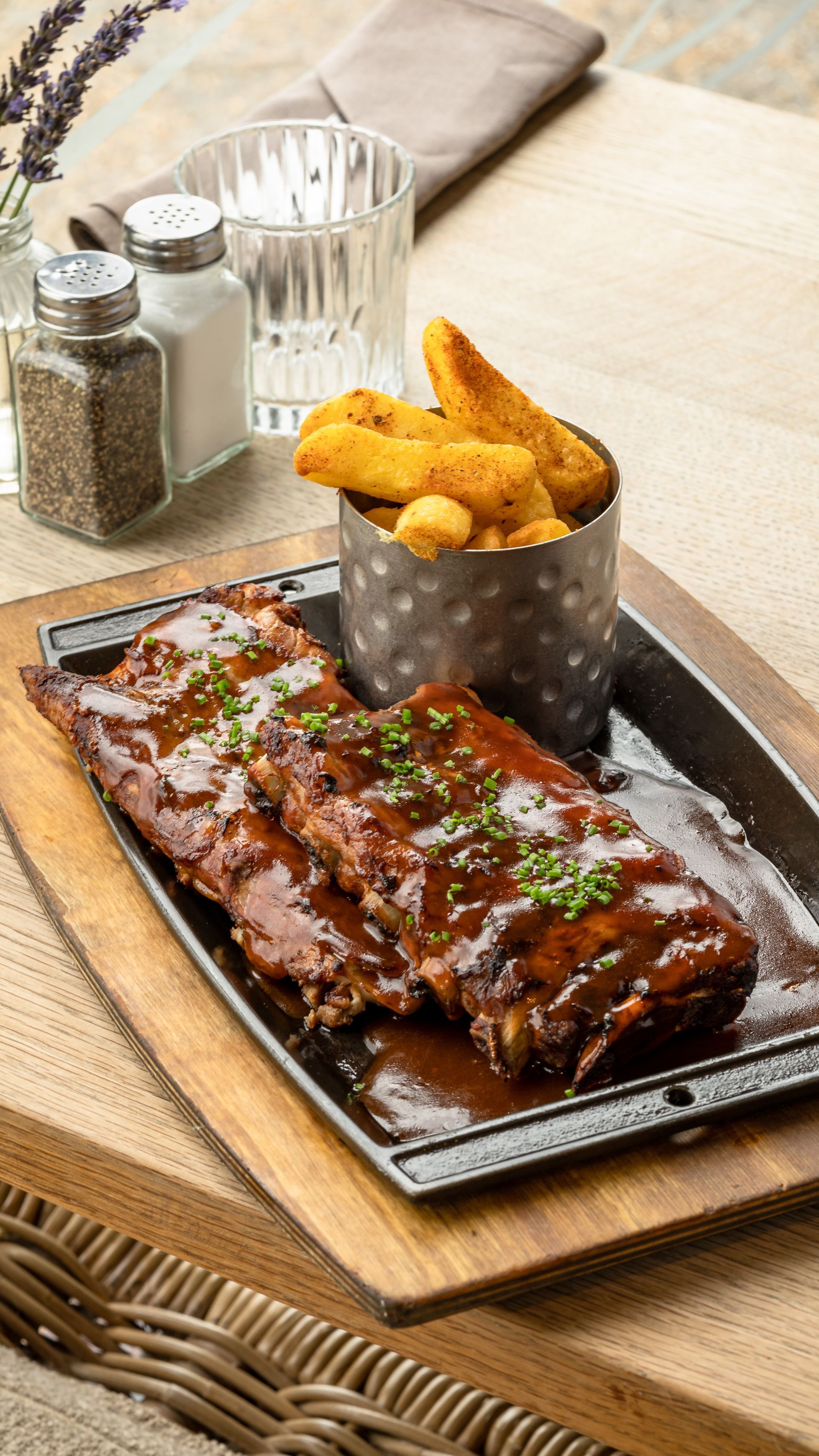 BBQ ribs with fries, served on a wooden platter.